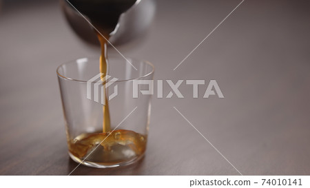 coffee pour into tumbler glass on walnut table coffee pour into tumbler glass on walnut table 74010141