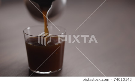 coffee pour into tumbler glass on walnut table coffee pour into tumbler glass on walnut table 74010143