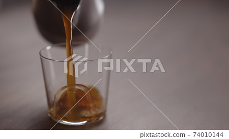 coffee pour into tumbler glass on walnut table coffee pour into tumbler glass on walnut table 74010144