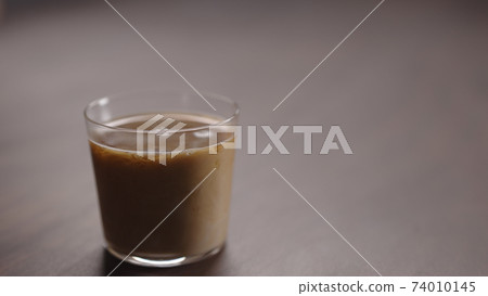 milk pour into tumbler glass with coffee on walnut table milk pour into tumbler glass with coffee on walnut table 74010145