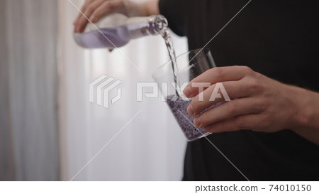 man pouring purple drink into tumbler glass near window man pouring purple drink into tumbler glass near window 74010150