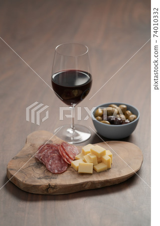 olives, salami and vintage cheese with glass of red wine on walnut table olives, salami and vintage cheese with glass of red wine on walnut table 74010332