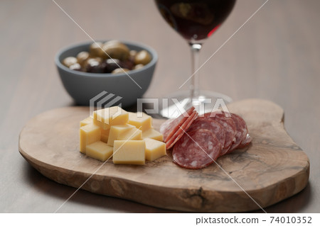 olives, salami and vintage cheese with glass of red wine on walnut table olives, salami and vintage cheese with glass of red wine on walnut table 74010352