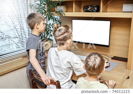 Delighted children sit near table looking into large display 74011223