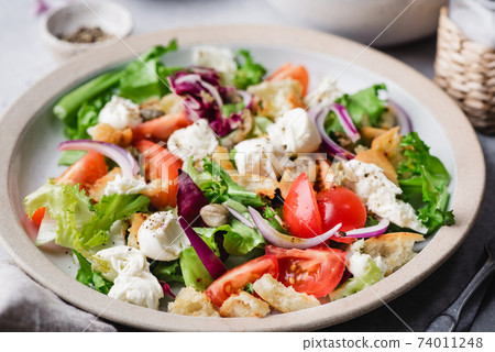 Italian summer salad with mozzarella cheese, croutons, tomatoes and capers 74011248