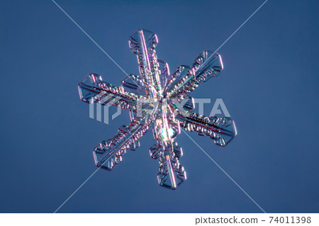 Snowflake on smooth gradient background. Macro photo of real snow crystal on glass surface. This is small snowflake with unusual pattern. Snowflake on smooth gradient background. Macro photo of real snow crystal on glass surface. This is small snowflake with unusual pattern. 74011398