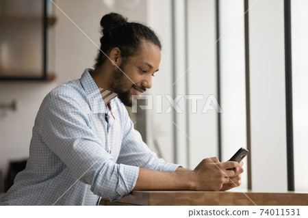 Positive young black male having pleasure playing game by cell 74011531