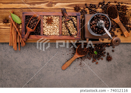 Various of roasted coffee beans in wooden box with manual coffee grinder setup on shabby wooden background. 74012116