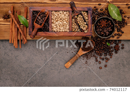 Various of roasted coffee beans in wooden box with manual coffee grinder setup on shabby wooden background. 74012117
