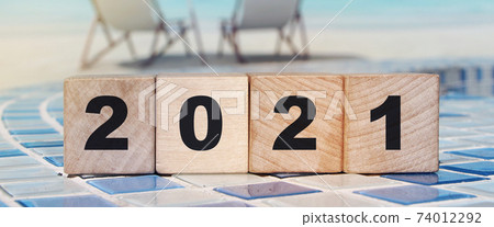 Wood cube number 2021 on planks on tropical beach background. New year concept and happy holiday idea 74012292