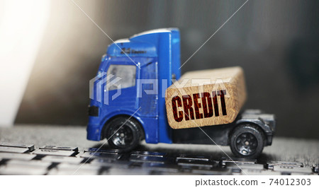 Cardboard box with credit word on wooden block and mini forklift truck with ketboard background. Logistics and transportation management ideas and Industry business commercial concept Cardboard box with credit word on wooden block and mini forklift truck with ketboard background. Logistics and transportation management ideas and Industry business commercial concept 74012303