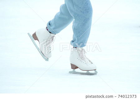 legs of a woman ice skating on an ice rink. hobbies and leisure. winter sports legs of a woman ice skating on an ice rink. hobbies and leisure. winter sports 74012373