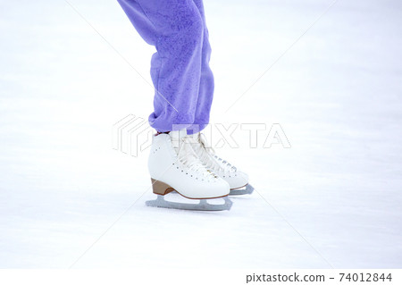 legs of a woman in white skates on an ice rink. hobbies and leisure. winter sports legs of a woman in white skates on an ice rink. hobbies and leisure. winter sports 74012844