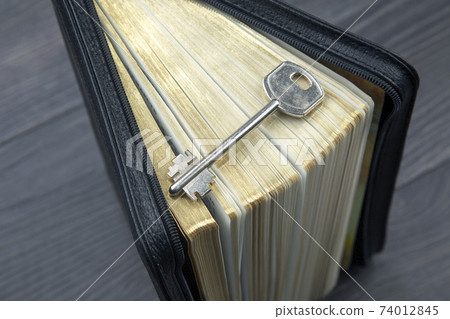 the key lies on an open bible book. the key lies on an open bible book. 74012845