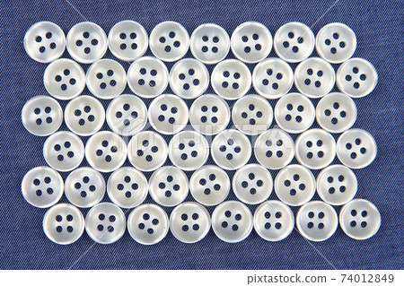Plastic shiny buttons for clothes on a fabric background. Fashion and clothing. Factory industry Plastic shiny buttons for clothes on a fabric background. Fashion and clothing. Factory industry 74012849