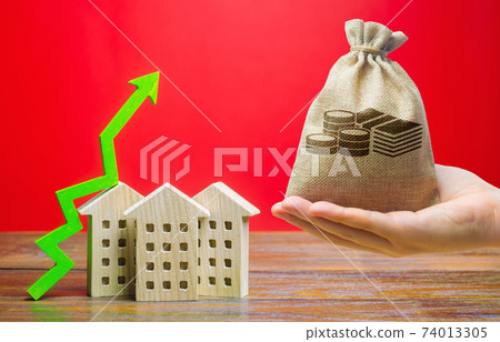 Money bag and wooden houses with an arrow up. Real estate concept. Business and finance. Savings on the purchase of housing and apartments. Mortgage, loan, taxes, debts. Family home budget. Money bag and wooden houses with an arrow up. Real estate concept. Business and finance. Savings on the purchase of housing and apartments. Mortgage, loan, taxes, debts. Family home budget. 74013305