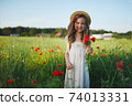 cute little girl in meadow with red poppies 74013331