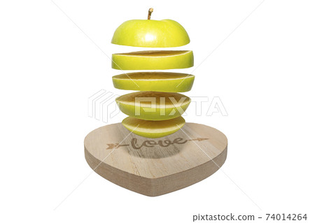 A stack of green apples falls or flies over a heart-shaped board.Creative food levitation 74014264