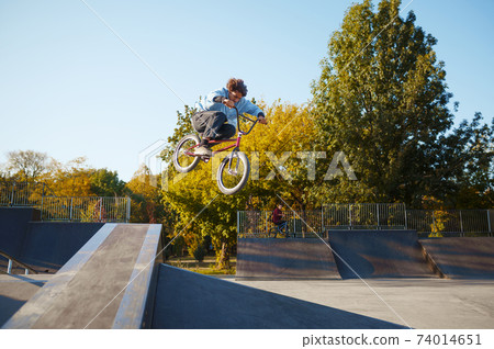 Bmx biker rides by railing in skatepark 74014651