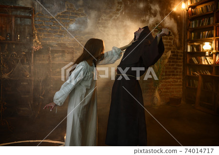 Exorcist casting out satan from young woman Exorcist casting out satan from young woman 74014717