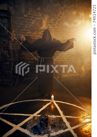 Exorcist in hood reads spell near the magic circle Exorcist in hood reads spell near the magic circle 74014725