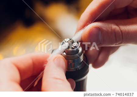 Specialist replaces spring for smoking vape.Professional maintaining electronic cigarette in shop.Fix broken vaping device and quit smoking nicotine cigarettes. Specialist replaces spring for smoking vape.Professional maintaining electronic cigarette in shop.Fix broken vaping device and quit smoking nicotine cigarettes. 74014837