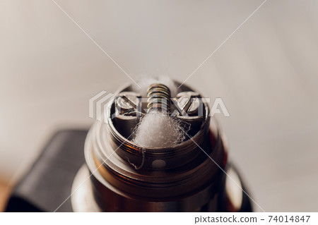Specialist replaces spring for smoking vape.Professional maintaining electronic cigarette in shop.Fix broken vaping device and quit smoking nicotine cigarettes. Specialist replaces spring for smoking vape.Professional maintaining electronic cigarette in shop.Fix broken vaping device and quit smoking nicotine cigarettes. 74014847