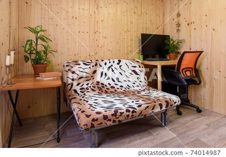 Interior of a country house room, next to the sofa there is a computer table, on the other side there is a coffee table 74014987