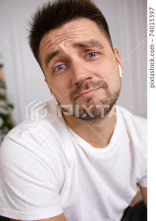 young man in earphones is talking to somebody 74015397