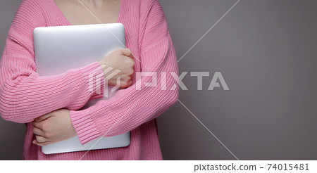 girl in a pink sweater presses a silver laptop to her chest girl in a pink sweater presses a silver laptop to her chest 74015481