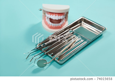 Dental mirror, forceps extractor, scaler, cotton pliers and jaw cast on a blue background 74015658