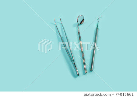 Flat lay shoot of metal steel dental tools on a blue background. Toohcare, dental health concept. 74015661
