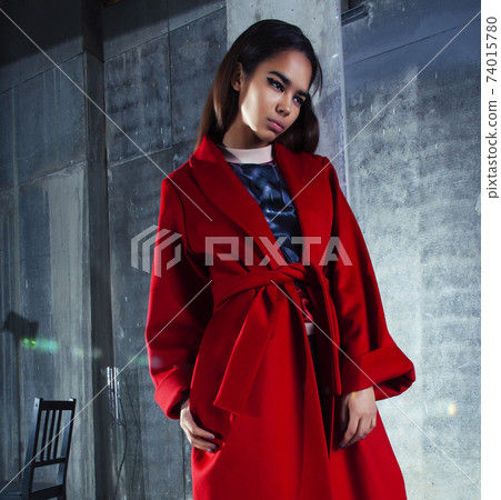 young pretty african american woman in luxury red coat posing fashionable on empty parking building, lifestyle rich people concept 74015780