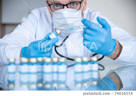 Doctor in the laboratory in medical mask and gloves prepares vaccines for coronavirus. Doctor in the laboratory in medical mask and gloves prepares vaccines for coronavirus. 74016554