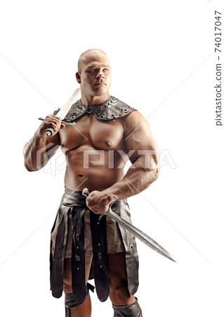 Severe barbarian in leather costume with sword. Portrait of balded muscular gladiator. Studio shot. Isolated on white background Severe barbarian in leather costume with sword. Portrait of balded muscular gladiator. Studio shot. Isolated on white background 74017047