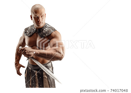 Severe barbarian in leather costume with sword. Portrait of balded muscular gladiator. Studio shot. Isolated on white background Severe barbarian in leather costume with sword. Portrait of balded muscular gladiator. Studio shot. Isolated on white background 74017048