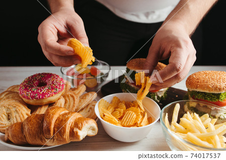 Overweight man overeating unhealthy junk food 74017537