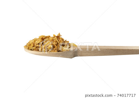 Crispy carmelized fried onion flakes in wooden spoon isolated on white background. Spices and food ingredients. Crispy carmelized fried onion flakes in wooden spoon isolated on white background. Spices and food ingredients. 74017717