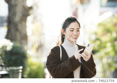 A young woman looking for a destination on her smartphone A young woman looking for a destination on her smartphone 74022759