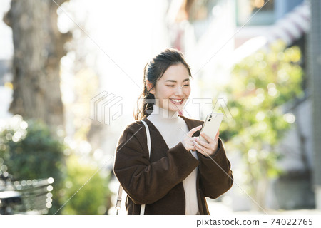 尋找在她的智能手機上一個年輕女子目的地 尋找在她的智能手機上一個年輕女子目的地 74022765