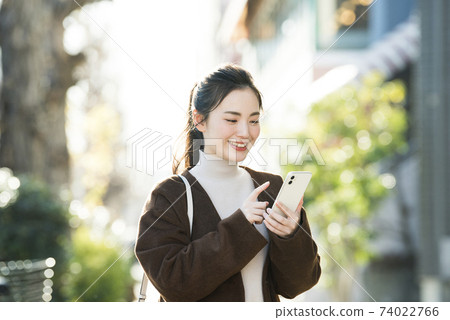 尋找在她的智能手機上一個年輕女子目的地 尋找在她的智能手機上一個年輕女子目的地 74022766
