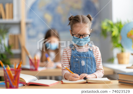 Kids are wearing facemasks learning in class Kids are wearing facemasks learning in class 74023529