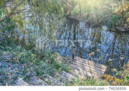 Wooden steps to calm narrow river in early autumn morning Wooden steps to calm narrow river in early autumn morning 74026809