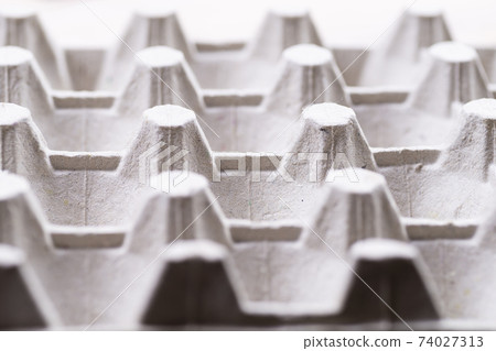 Cardboard box for raw eggs close-up. Gray egg carton. Recycling paper container for packing raw eggs. Packing material. Egg crate Cardboard box for raw eggs close-up. Gray egg carton. Recycling paper container for packing raw eggs. Packing material. Egg crate 74027313