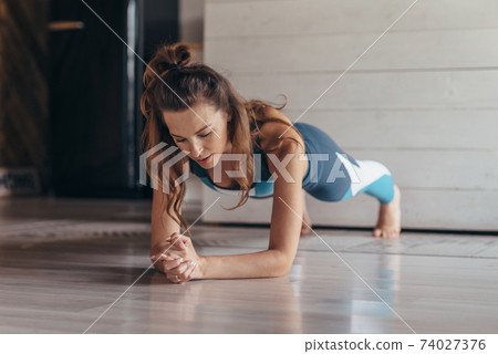Fit woman doing plank exercise, workout at home 74027376