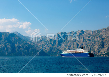 A huge multi-deck cruise liner in Kotor Bay, against the backdrop of a mountain above the city of Dovrota and Ljuta in Montenegro. A huge multi-deck cruise liner in Kotor Bay, against the backdrop of a mountain above the city of Dovrota and Ljuta in Montenegro. 74029214