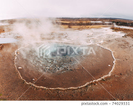 Geyser Valley in the southwest of Iceland. The famous tourist attraction Geysir. Geothermal zone Haukadalur. Strokkur geyser on the slopes of Laugarfjall hill. 74029331