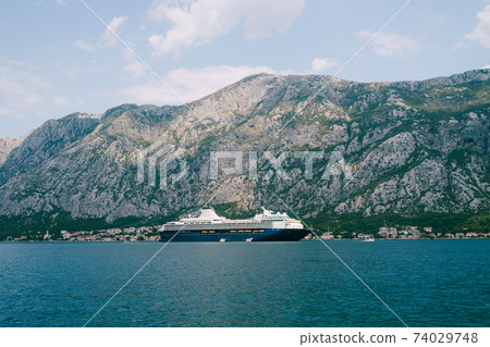 A huge multi-deck cruise liner in Kotor Bay, against the backdrop of a mountain above the city of Dovrota and Ljuta in Montenegro. A huge multi-deck cruise liner in Kotor Bay, against the backdrop of a mountain above the city of Dovrota and Ljuta in Montenegro. 74029748