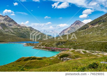 Bernina Express at the White Lake in Ospizio Bernina, Engadin, Switzerland Bernina Express at the White Lake in Ospizio Bernina, Engadin, Switzerland 74029891