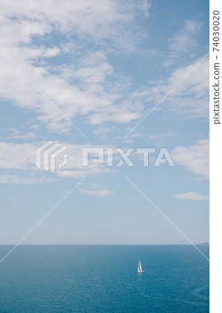 Travel concept background - small sailboat in the sea with blue sky with clouds. Travel concept background - small sailboat in the sea with blue sky with clouds. 74030020
